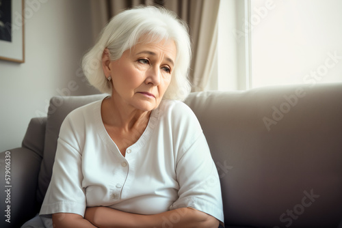 Mature woman sitting on the sofa feeling sad and alone. Upset elderly 70s female have headache while in living room at home. Generative ai.