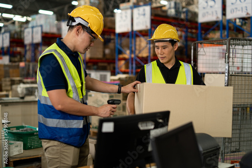 Asian warehouse workers team Checks Stock and Inventory on Desktop Computer in retail warehouse full of shelves with goods. teamwork at warehouse storage department.