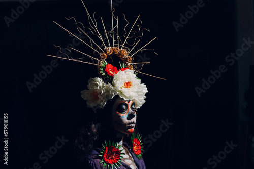 Fototapeta Naklejka Na Ścianę i Meble -  Woman with mexican skull halloween makeup on dark background. Day of the dead aka Dia de Muertos and halloween concept.