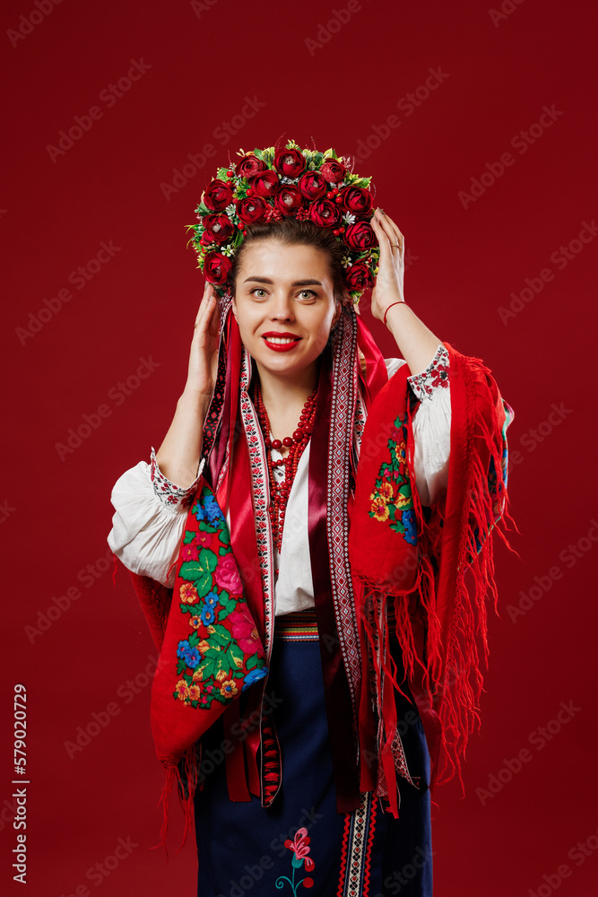 Portrait of ukrainian woman in traditional ethnic clothing and floral red wreath on viva magenta studio background. Ukrainian national embroidered dress call vyshyvanka. Pray for Ukraine