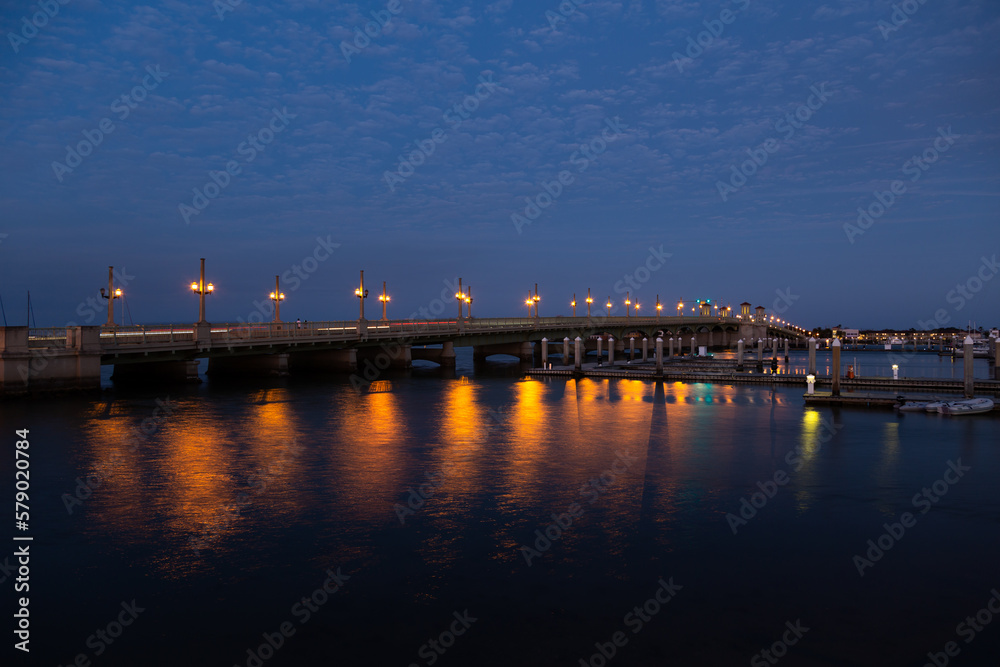 Night view of the lighted 1927 double-leaf bascule Bridge of Lions connecting downtown to Anastasia Island across Matanzas Bay and harbour piers, St. Augustine, Florida