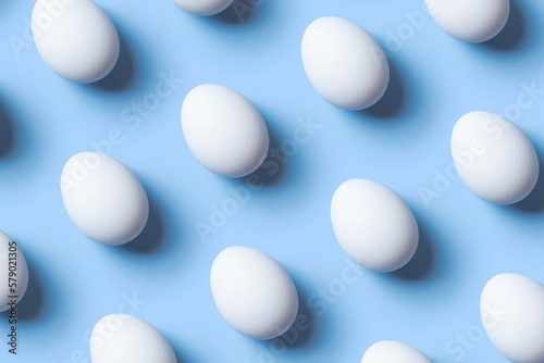 Creative composition with pattern from white eggs on blue background. Copy space