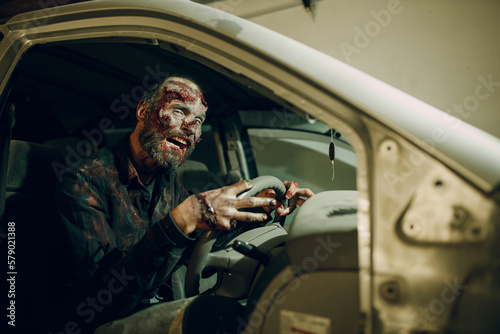 Zombie driving car to halloween party concept. Make up skin and blood face