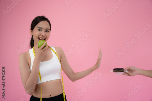 Diet and dieting. Beauty slim female body confuse donut. Woman in exercise clothes achieves weight loss goal for healthy life, crazy about thinness, thin waist, nutritionis