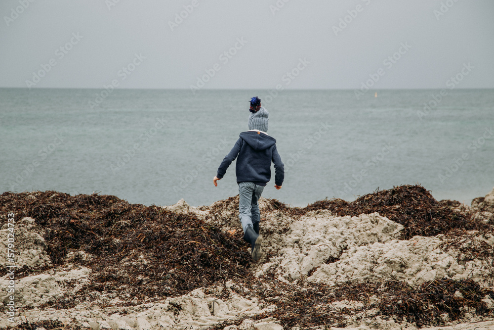 Young boy exploring coastal beach on cold winter day Young boy exploring coastal beach on cold winter day