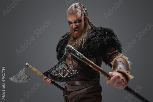 Shot of ancient nordic vandal dressed in leather armor and black fur with paired axes.