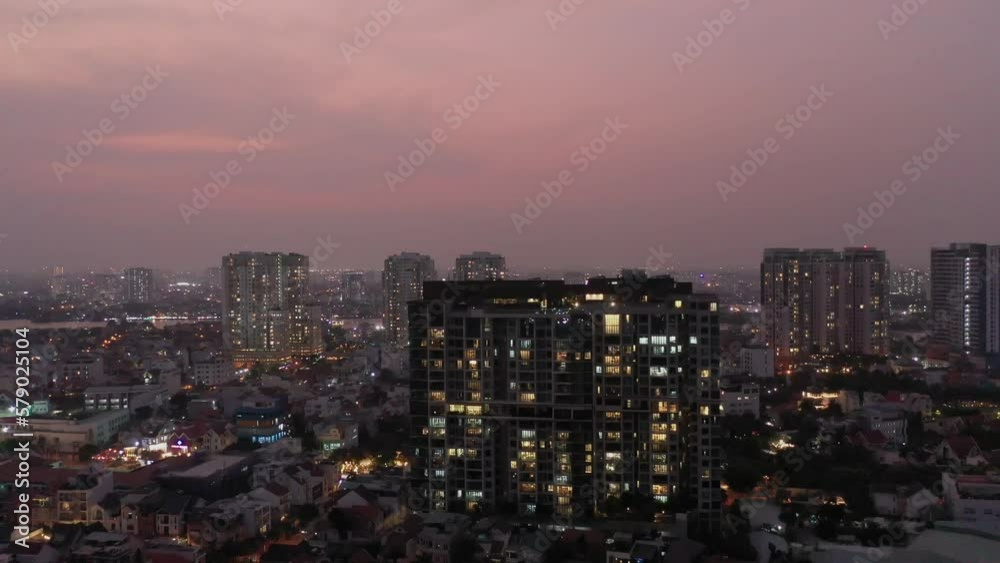 Urban twilight descending drone shot with city lights, buildings and houses against a colorful sky with river in the distance. A generic and interesting city, suburb establishing shot. Part one Urban twilight descending drone shot with city lights, buildings and houses against a colorful sky with river in the distance. A generic and interesting city, suburb establishing shot. Part one