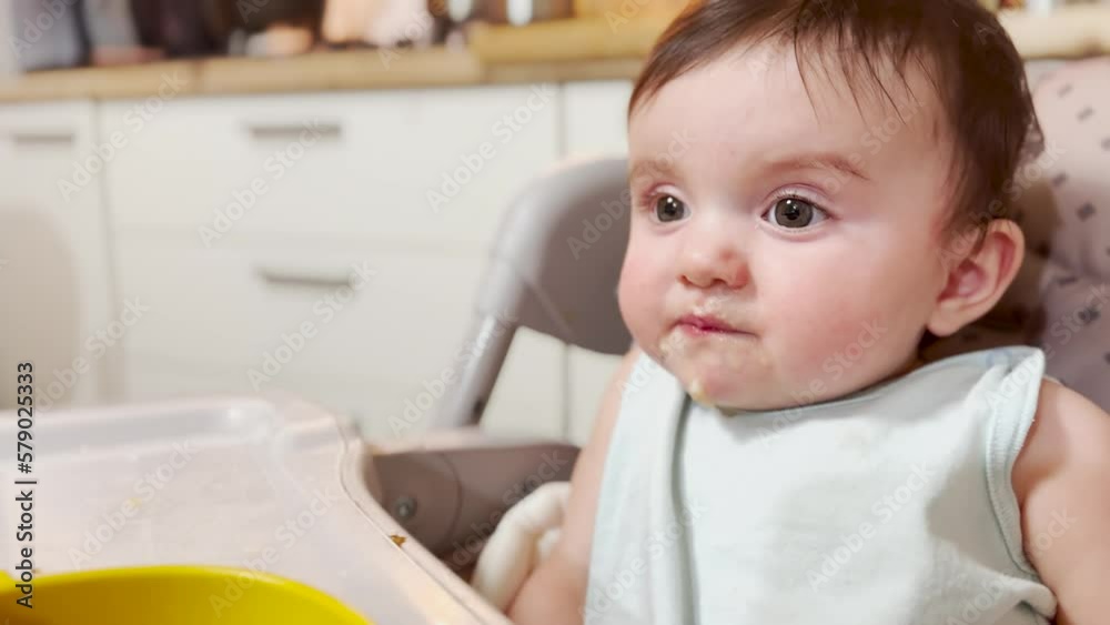 mom feeds baby at the table. dirty a baby newborn dirty mouth eats from a spoon. happy family kindergarten proper nutrition newborn. baby eats fruit puree from a spoon lifestyle mom feeds baby at the table. dirty a baby newborn dirty mouth eats from a spoon. happy family kindergarten proper nutrition newborn. baby eats fruit puree from a spoon lifestyle