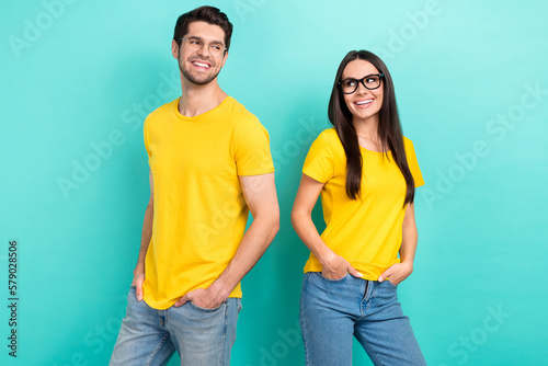 Photo of two teammates partners yellow t-shirts denim jeans hands pockets stylish ray ban glasses good job isolated on aquamarine color background