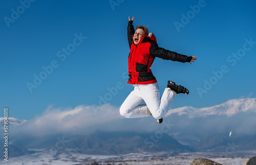 Young happy woman jumping on mountains background in winter season