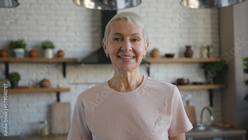 Portrait of happy elderly woman in pink t-shirt looking at the camera and smiling