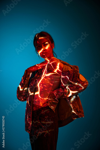 Futuristic style portrait of young woman with digital neon filter lights on clothes over dark blue background. Concept of art, fashion, cyberpunk, futurism and creativity