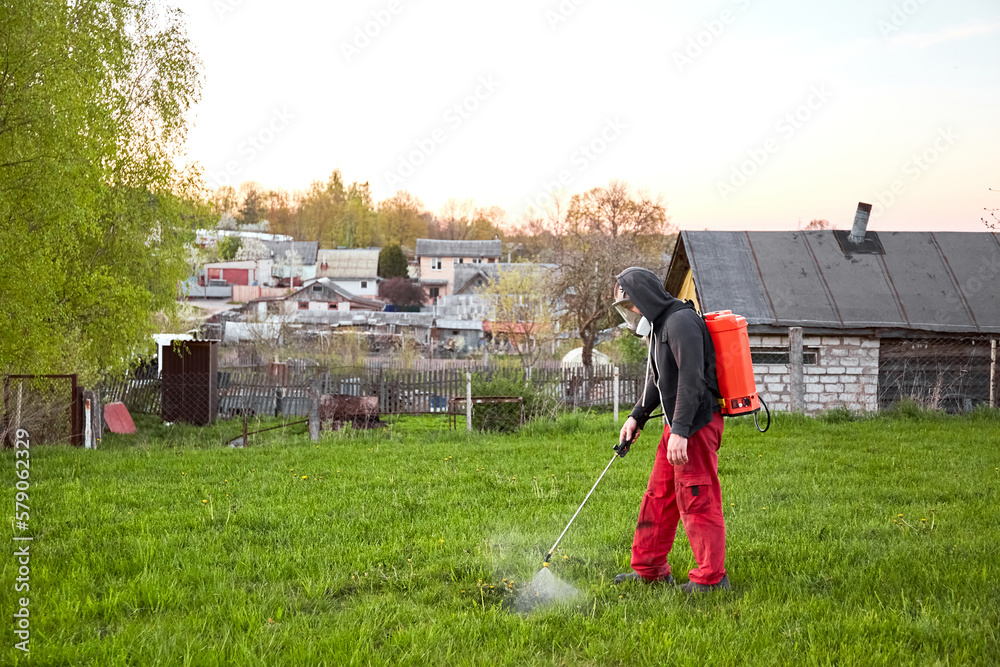 Farmers spraying pesticide on lawn field wearing protective
