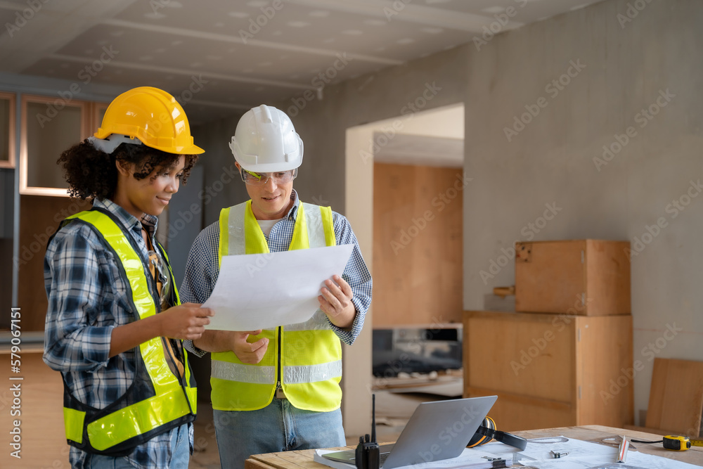 Architect colleagues mixed race working as a team discussing data working and tablet, laptop with on on architectural project at construction site at desk. Architect colleagues mixed race working as a team discussing data working and tablet, laptop with on on architectural project at construction site at desk.