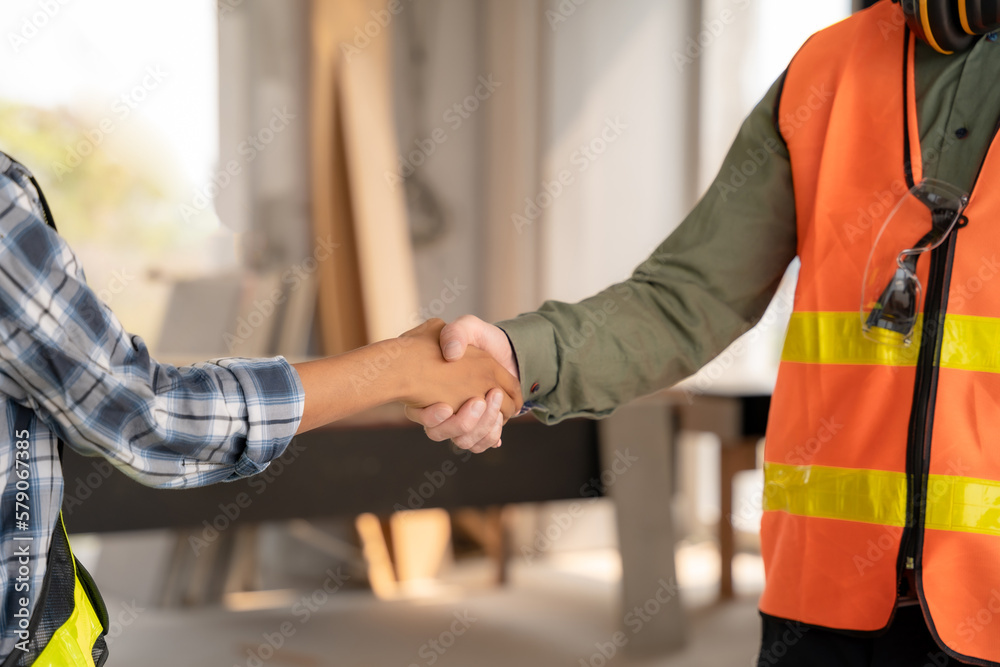 Construction workers, architects and engineers shake hands while working for teamwork and cooperation after completing an agreement in an office facility, successful cooperation concept. Construction workers, architects and engineers shake hands while working for teamwork and cooperation after completing an agreement in an office facility, successful cooperation concept.