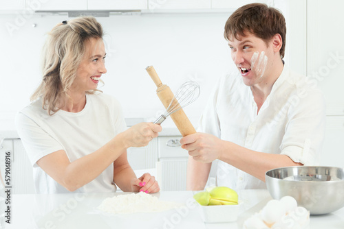 Husband and wife quarrel in kitchen while cooking. Comic and cheerful confrontation between man and woman in kitchen. Background..