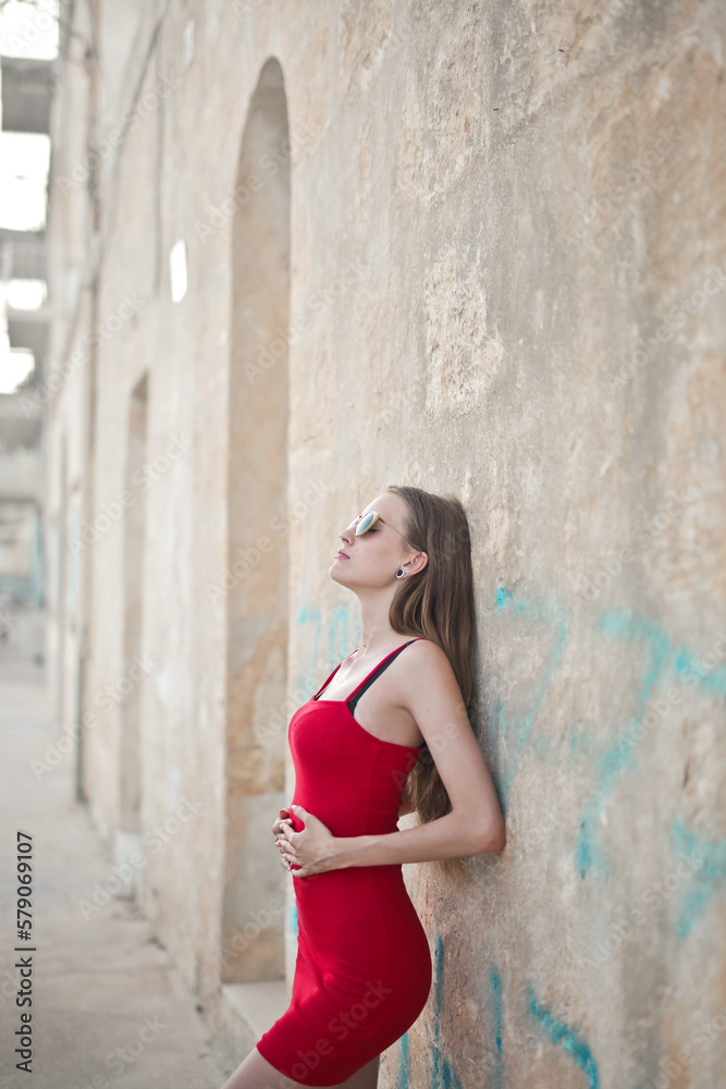 beautiful woman leaning against a wall of a house