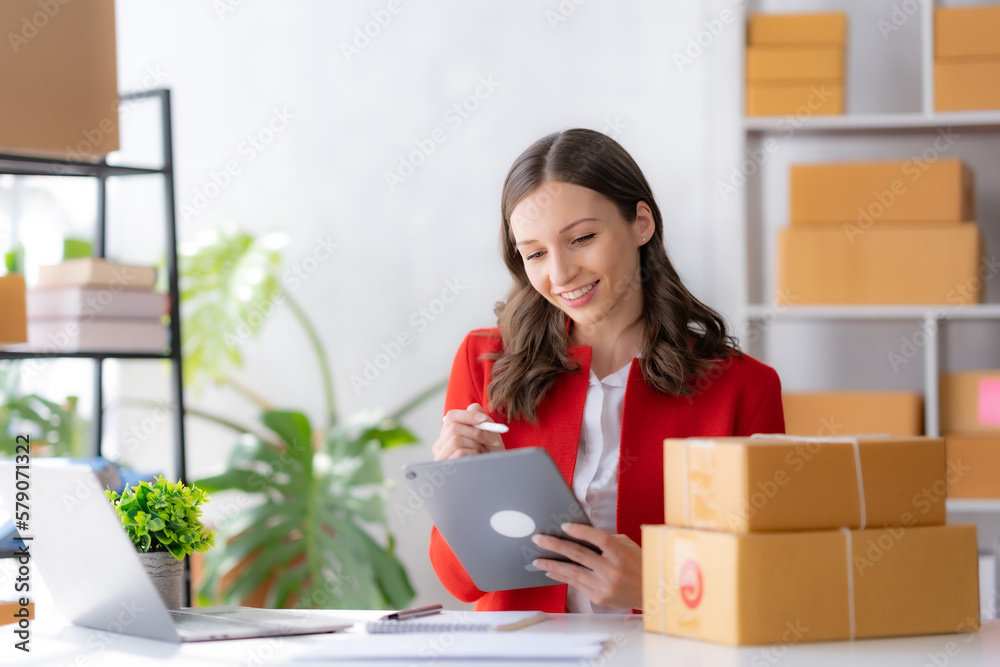 Female ecommerce business owner prepares package box for customer and delivery check balance. SME. Female ecommerce business owner prepares package box for customer and delivery check balance. SME.