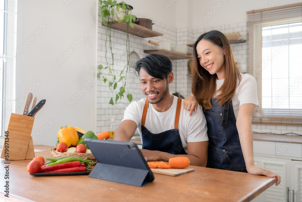Happy Asian couple learning to cook through tablet together. Happy Asian couple learning to cook through tablet together.