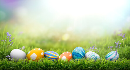 A collection of painted easter eggs celebrating a Happy Easter on a spring day with green grass meadow background with copy space.