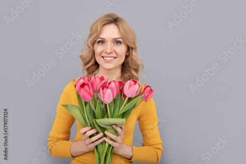 positive girl hold flowers for spring holiday on grey background