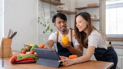 Happy Asian couple learning to cook through tablet together.