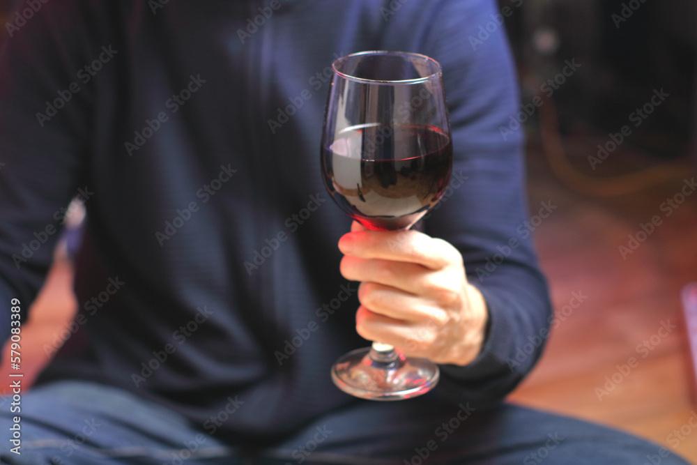 person holding a glass of wine while sitting person holding a glass of wine while sitting