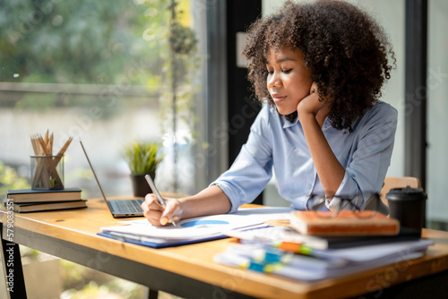 Black woman sitting in front of her considering work, office work Business woman sitting thinking work concept, Write a plan