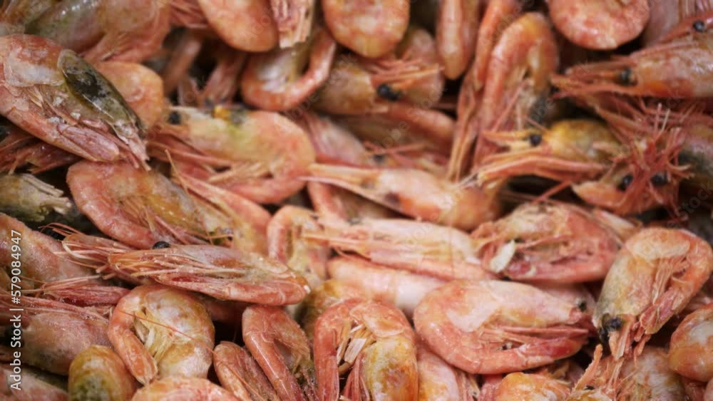 Pink fresh frozen shrimps with ice in a supermarket or fish shop. Uncooked seafood close up background. Fresh frozen prawns, delicacies, sea food concept, close up. Pink fresh frozen shrimps with ice in a supermarket or fish shop. Uncooked seafood close up background. Fresh frozen prawns, delicacies, sea food concept, close up.
