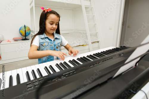 a cute little girl learning to play the synthesizer.