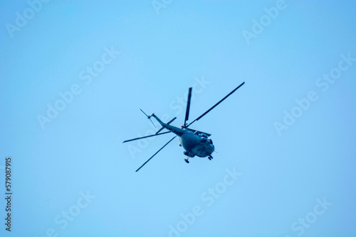 Military helicopters is flying against isolated blue sky 