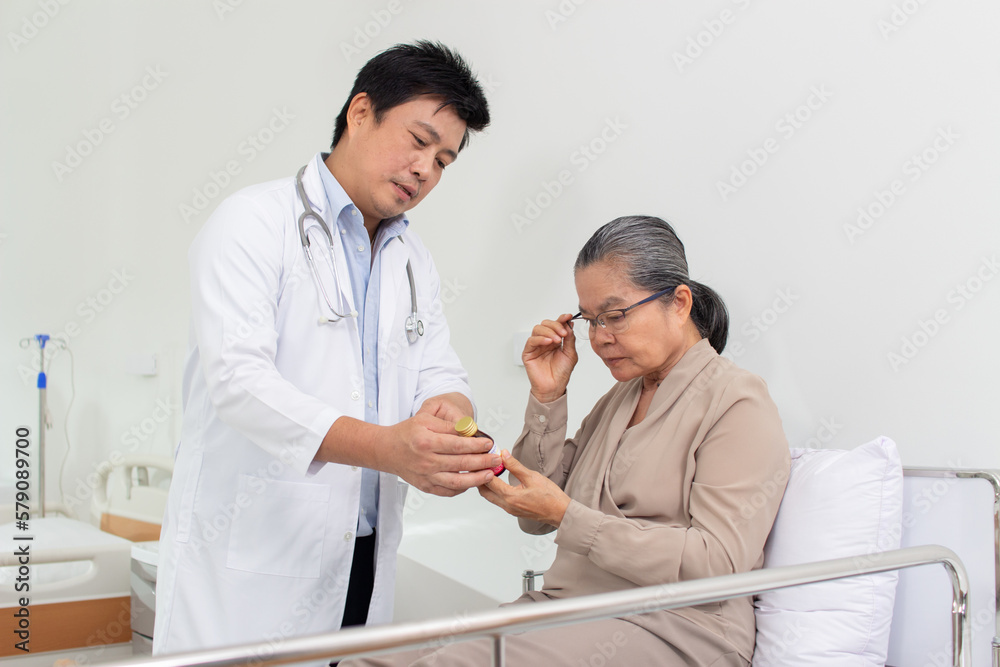 Asian male doctor explaining medicine to elderly female patient in hospital. Asian male doctor explaining medicine to elderly female patient in hospital.