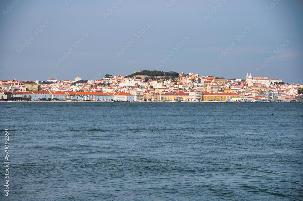 Distant view of Lisbon's downtown skyline across the Tagus River, under a bright blue sky Distant view of Lisbon's downtown skyline across the Tagus River, under a bright blue sky