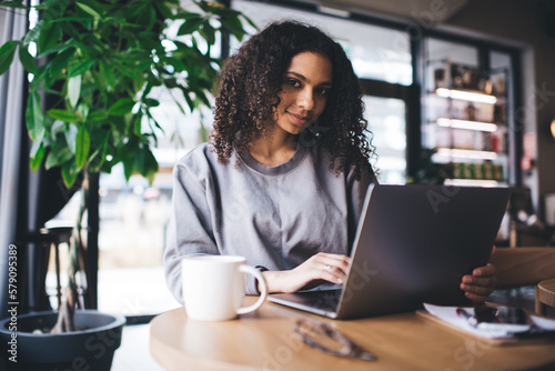 Smiling black woman working on laptop in cafe