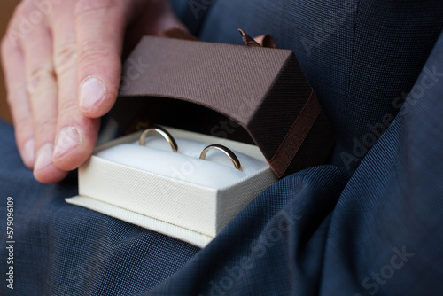 a man opens a gift box with wedding rings, showing them to the frame
