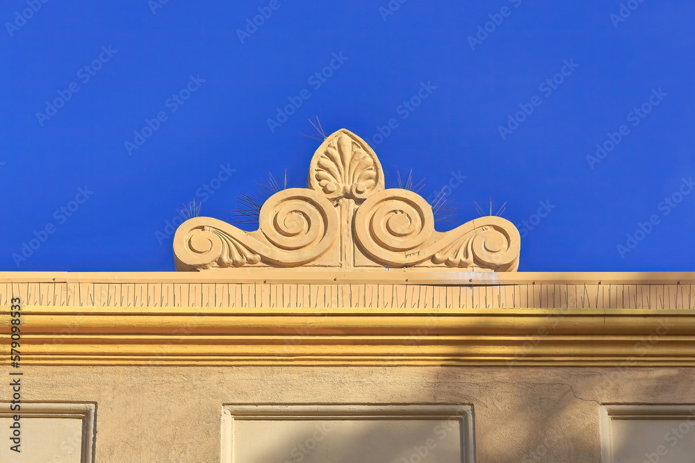 Baroque roof finial atop orangeyellow painted ArtDeco building on The