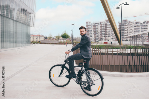 Elegant bearded young stylish businessman going to work by bike