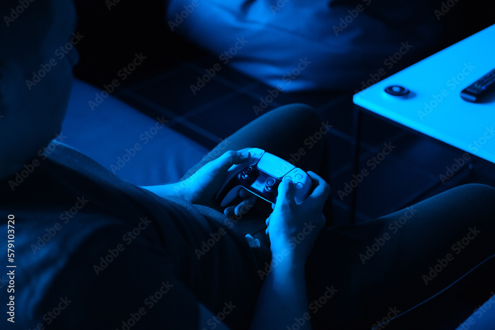 Young man playing console in neon blue