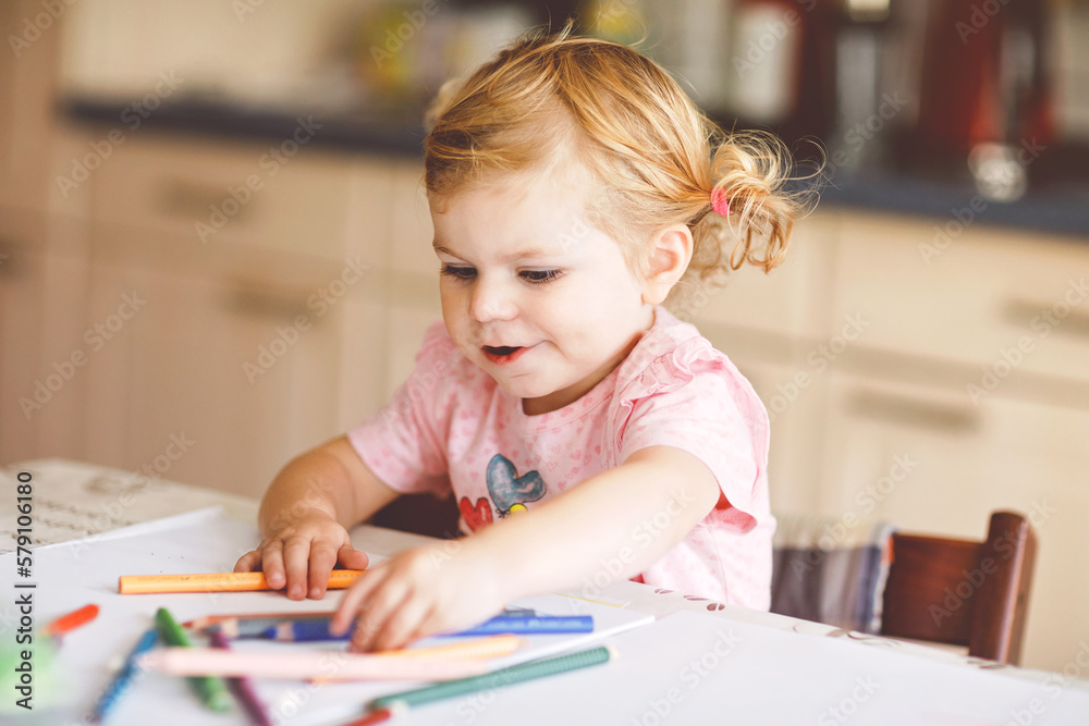 Cute adorable baby girl learning painting with pencils. Little toddler child drawing at home, using colorful felt tip pens. Healthy happy daughter experimenting with colors at home or nursery. Cute adorable baby girl learning painting with pencils. Little toddler child drawing at home, using colorful felt tip pens. Healthy happy daughter experimenting with colors at home or nursery.