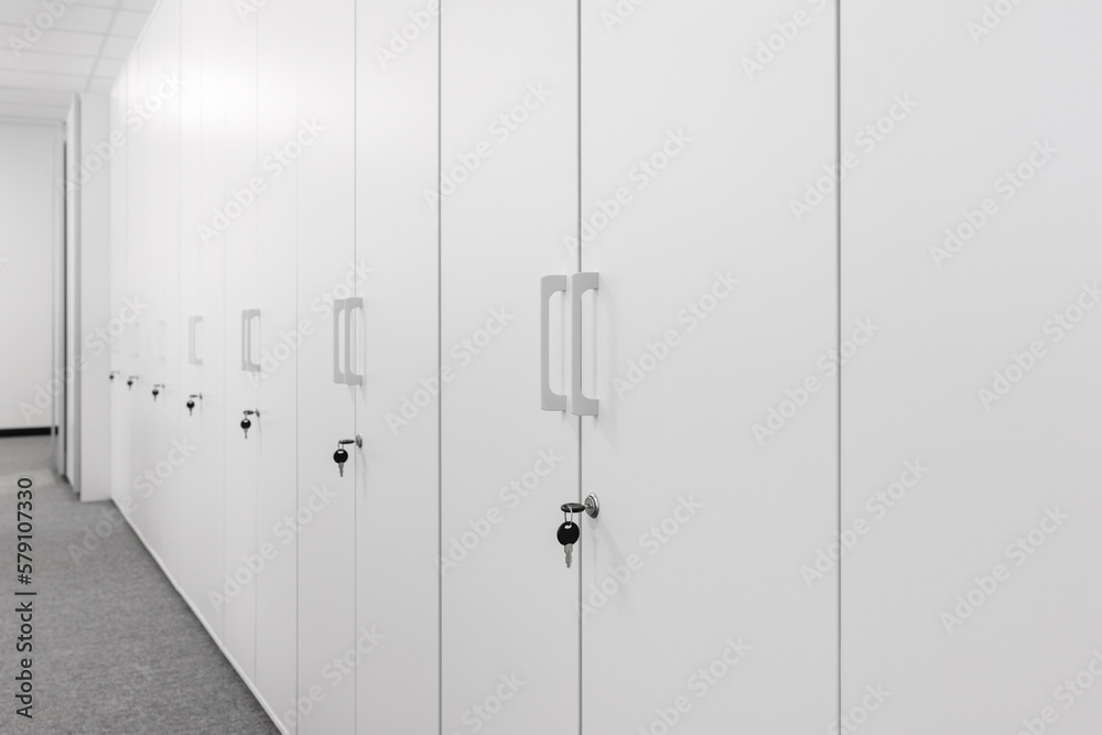A row of light office cabinets locked with a key. Shrinking perspective. Selective focus. A row of light office cabinets locked with a key. Shrinking perspective. Selective focus.