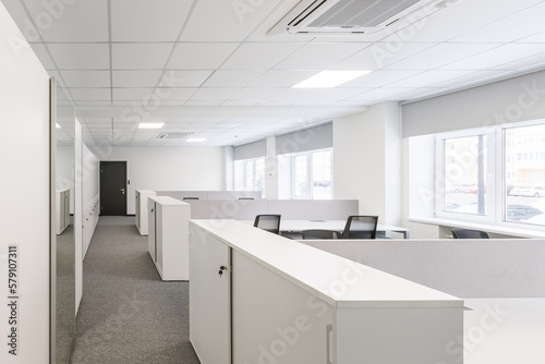 Modern corporate open office in minimalist modern design in whites and greys, empty office workstations.