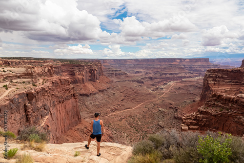 Man with scenic view from Shafer Trail Viewpoint in Canyonlands National Park near Moab, Utah, USA. Shafer Basin and La Sal Mountains in Colorado Plateau. Off road trails leading down the canyon