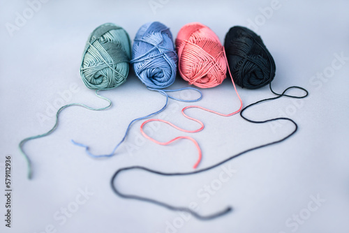 Four skeins of yarn with loosened threads on grey background.