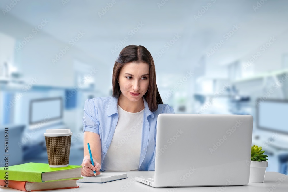 Happy female student sitting at the desk with laptop Happy female student sitting at the desk with laptop