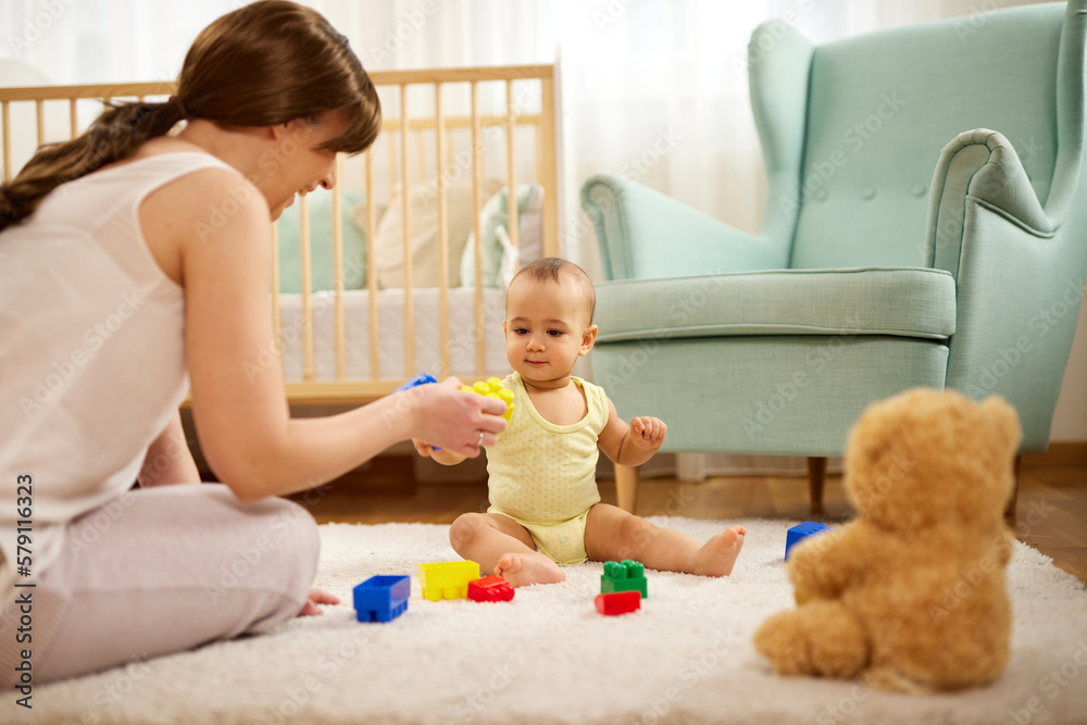 Mother and her baby boy playing with colored toy blocks at home Mother and her baby boy playing with colored toy blocks at home