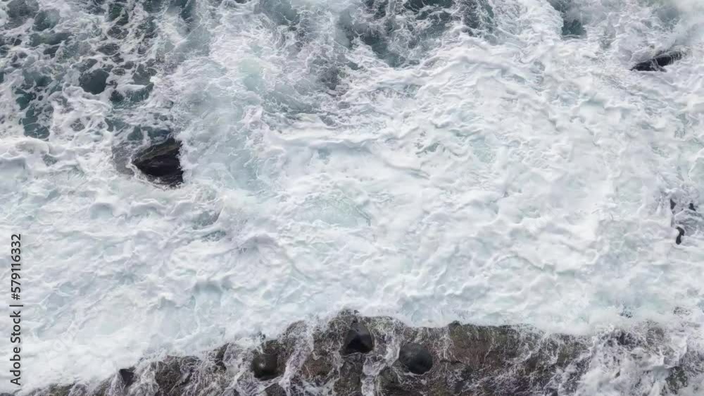 Aerial view of the waves breaking on the rocks. Splash water and foam on impact. Natural strength Aerial view of the waves breaking on the rocks. Splash water and foam on impact. Natural strength