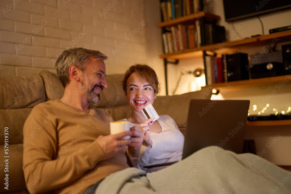 Mature couple doing online shopping using laptop and credit card at home Mature couple doing online shopping using laptop and credit card at home