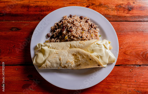 Top view of traditional gallo pinto with Quesillo served on wooden table.  Plate of nicaraguan gallopinto with quesillo on the table. typical nicaraguan foods photo