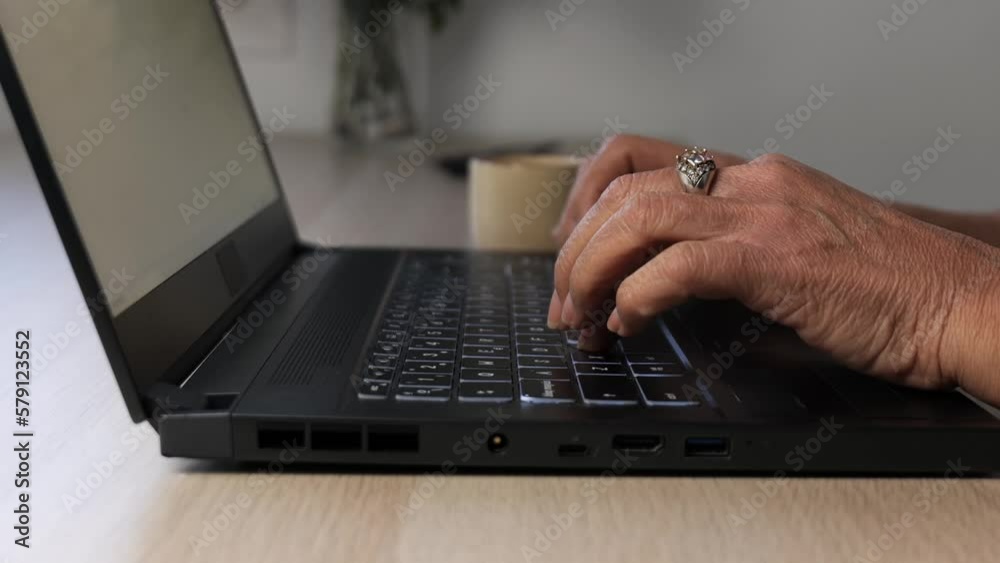 Close-up of the hands of an older woman typing on her laptop. Close-up of the hands of an older woman typing on her laptop.