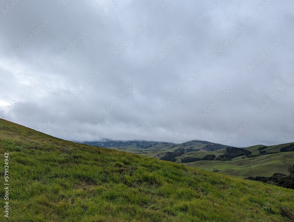 clouds over the mountains, green valley and hills landscape